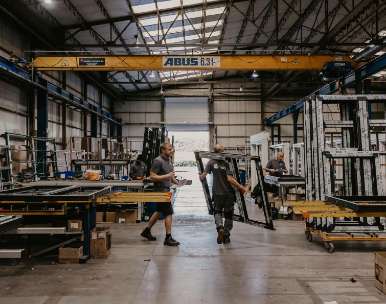 Collaborateurs portant un profilé de fenêtre dans l'atelier de production
