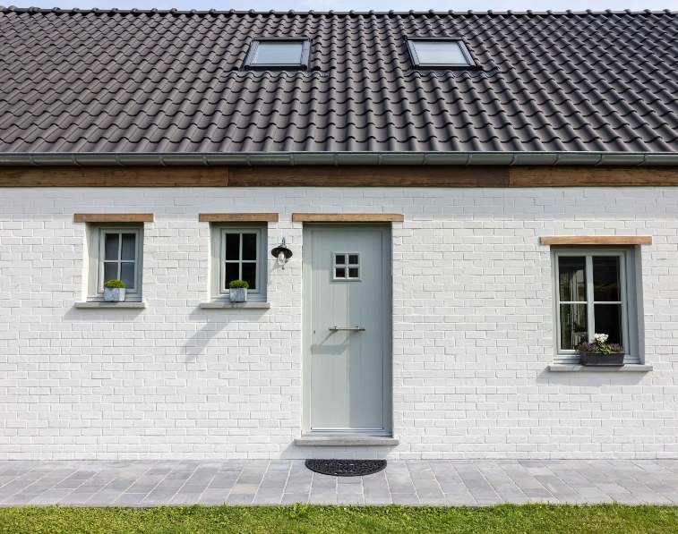 Porte d'entrée en PVC gris sur façade en briques blanches